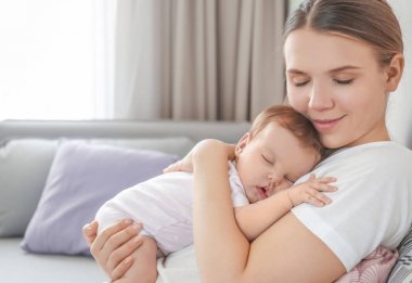Genç anne holding uyuyan bebek evde