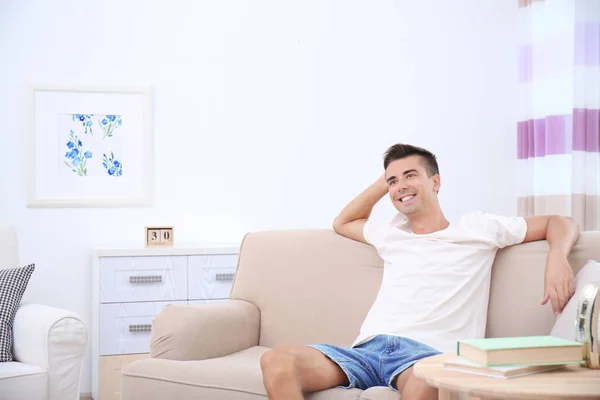 Jovem sentado no sofá em casa — Fotografia de Stock