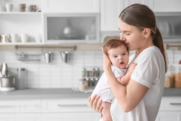Молодая мать держит ребенка на кухне — стоковое фото