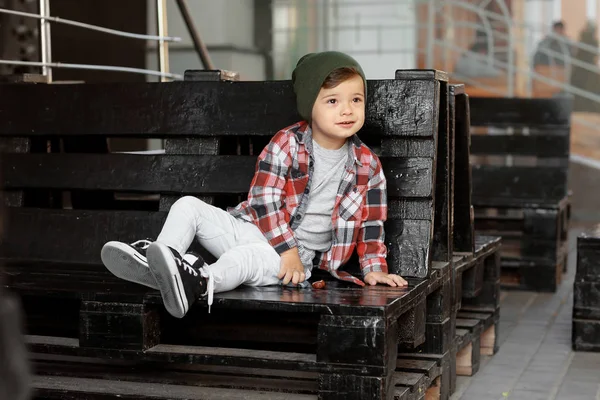 Adorable niño sentado en el banco en la cafetería al aire libre — Foto de Stock