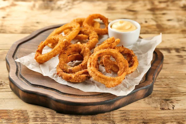 Anillos de cebolla frita con salsa sobre tabla de madera — Foto de Stock