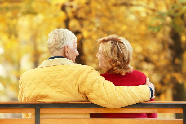 Idosos casal sentado no banco no parque de outono — Fotografia de Stock