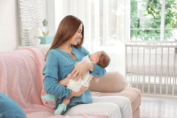 Ibu muda dengan bayi di sofa di rumah — Stok Foto