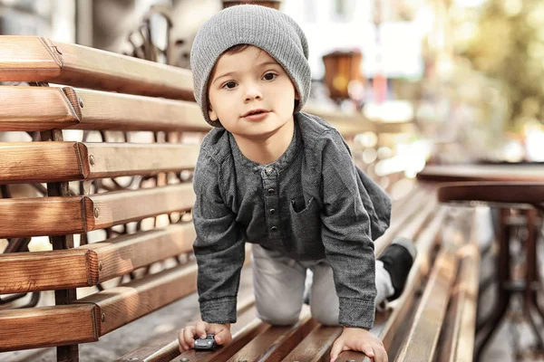 Adorable petit garçon sur banc dans un café extérieur — Photo