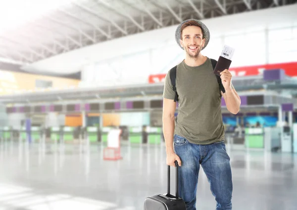 Young man with passport, ticket and baggage at airport