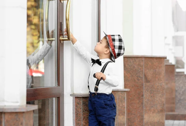 Adorabile bambino in piedi vicino all'ingresso dell'edificio all'aperto — Foto Stock