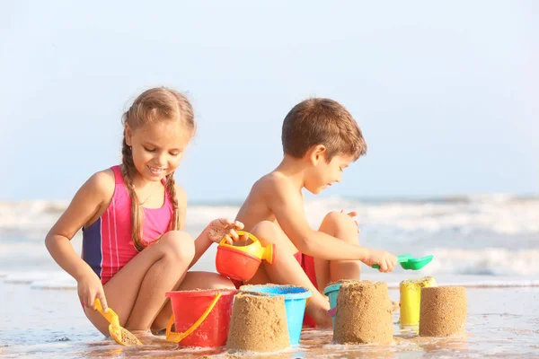 Lindos niños jugando con arena en la playa del mar — Foto de Stock