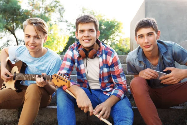 Teenager musicians sitting on steps outdoors — Stock Photo, Image
