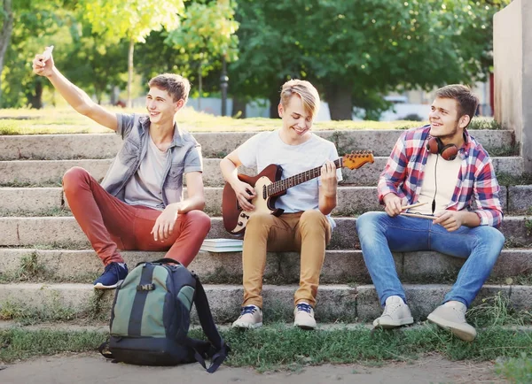 Músicos adolescentes tomando selfie enquanto sentados em degraus ao ar livre — Fotografia de Stock
