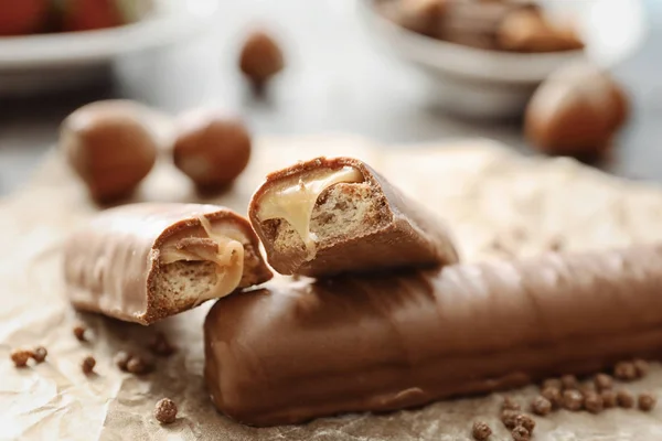 Tasty chocolate bars with caramel filling on parchment — Stock Photo, Image