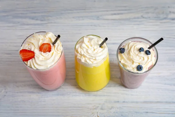 Milkshake diversi in bicchieri su sfondo di legno — Foto Stock