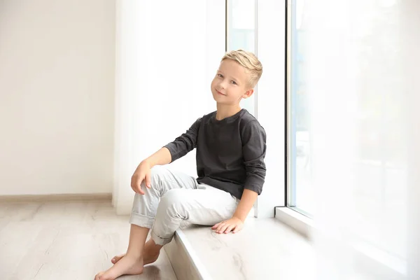 Lindo niño sentado cerca de la ventana en casa — Foto de Stock