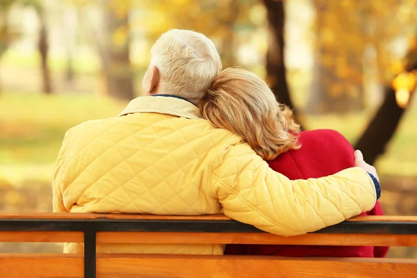 Idosos casal sentado no banco no parque de outono — Fotografia de Stock