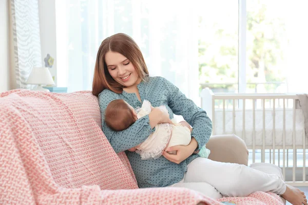 Ibu muda dengan bayi di sofa di rumah — Stok Foto