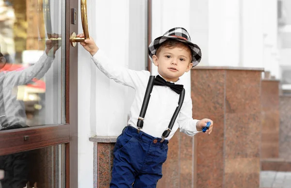Adorable petit garçon debout près de l'entrée du bâtiment à l'extérieur — Photo