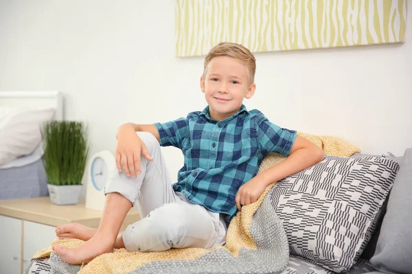 Ładny mały chłopiec siedzi na kanapie w domu — Zdjęcie stockowe