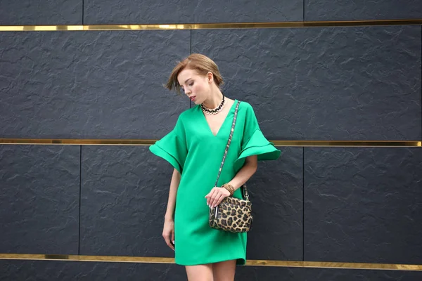 Beautiful woman in green dress near wall outdoors — Stock Photo, Image
