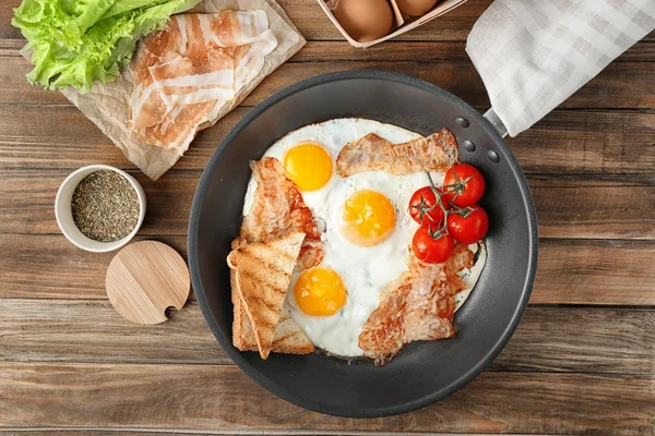 Сковородка с яйцами, беконом, тостами и помидорами черри — стоковое фото