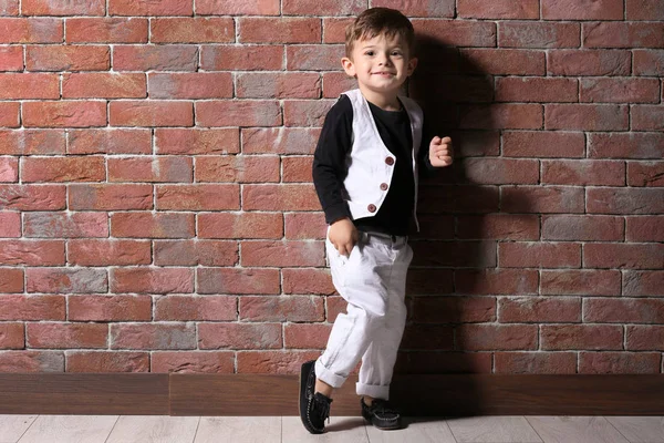 Adorable niño de pie cerca de la pared de ladrillo — Foto de Stock