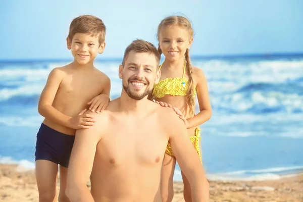 Cute little children with father on sea beach at resort — Stock Photo, Image