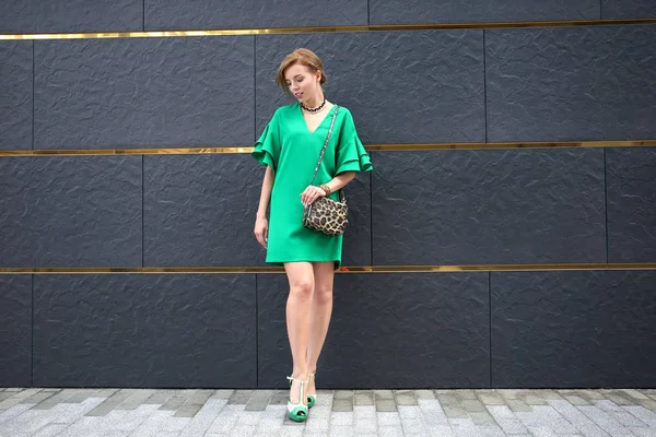 Duvar açık havada yakınındaki yeşil elbiseli güzel kadın — Stok fotoğraf