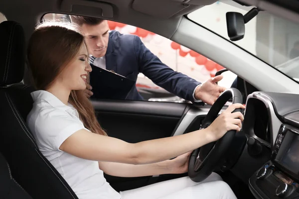 Vrouw zittend in de bestuurdersstoel van de nieuwe auto op salon — Stockfoto