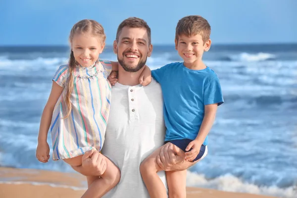 Симпатичные маленькие дети с отцом на морском пляже на курорте — стоковое фото