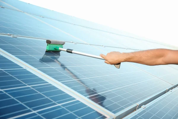 Рука работника, моющего солнечные панели после установки на открытом воздухе — стоковое фото
