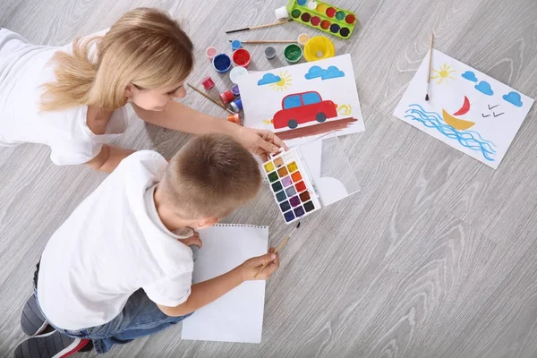 Mère avec mignon garçon peinture tableau sur feuille de papier, à l'intérieur — Photo