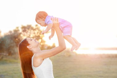 Güzel genç anne holding şirin bebek çocuk, açık havada