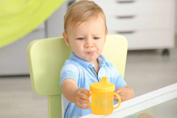 屋内でボトルを飲むとテーブルに座っているかわいい赤ちゃん — ストック写真