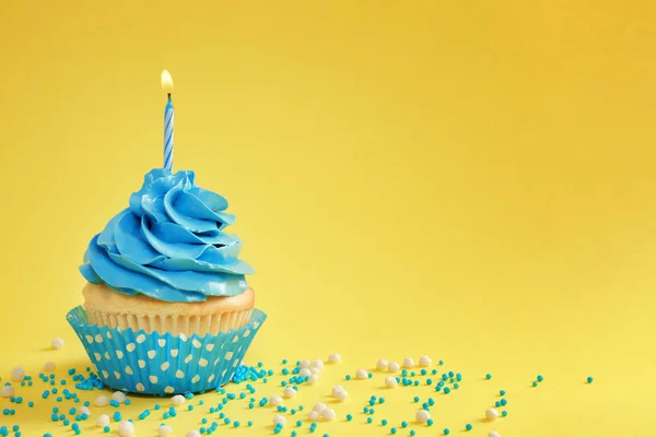 Sabroso cupcake con vela sobre fondo de color — Foto de Stock