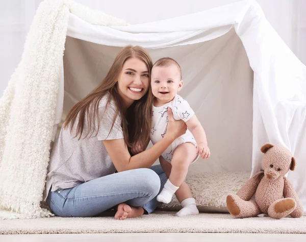 Młoda matka i słodkie dziecko bawiące się w namiocie w domu — Zdjęcie stockowe