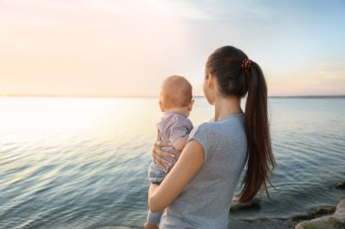 Güzel genç anne holding şirin bebek çocuk, açık havada