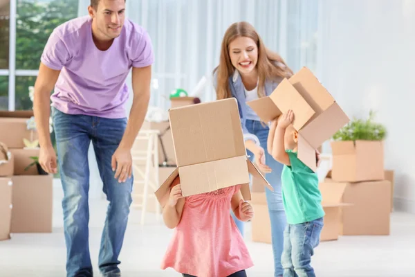 Pareja joven y lindos niños pequeños jugando con cajas móviles en su nueva casa — Foto de Stock