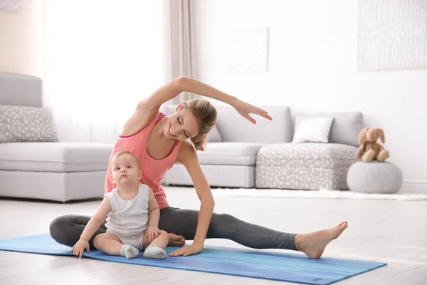Joven madre haciendo yoga con el bebé en casa —  Fotos de Stock