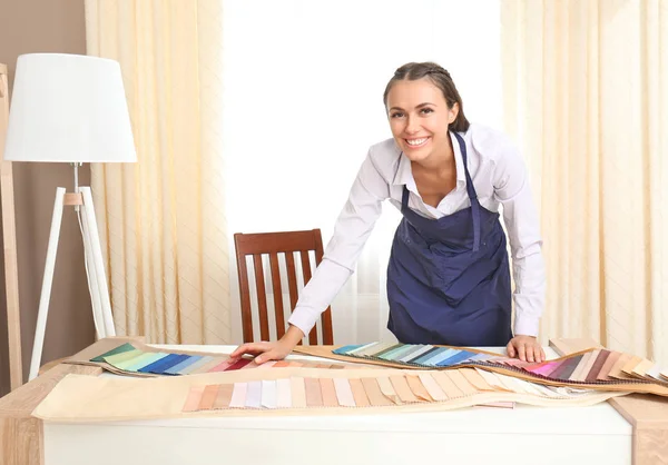 Jeune assistant de magasin avec des échantillons de tissu pour rideaux en magasin — Photo