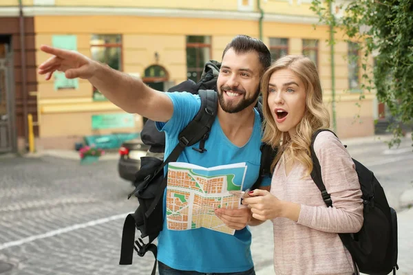 Pareja de turistas emocionados con mapa en la calle —  Fotos de Stock