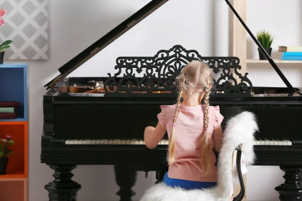 Девочка играет на пианино в помещении — стоковое фото
