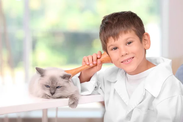 Мальчик в форме доктора играет с котом — стоковое фото