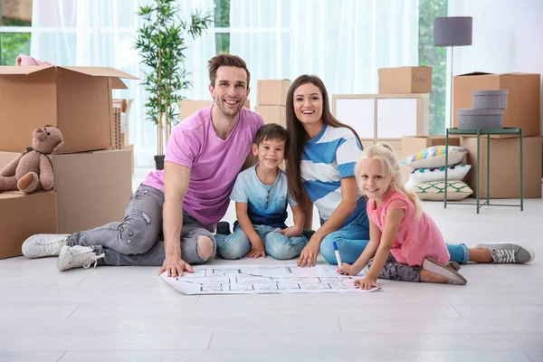Ευτυχισμένη οικογένεια με το σχέδιο του σπιτιού στον όροφο σε εσωτερικούς χώρους — Φωτογραφία Αρχείου