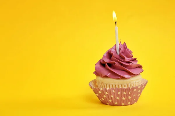 Sabroso cupcake con vela sobre fondo de color —  Fotos de Stock