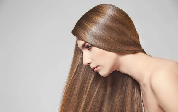 Young woman with beautiful long hair of caramel color on light background — Stock Photo, Image