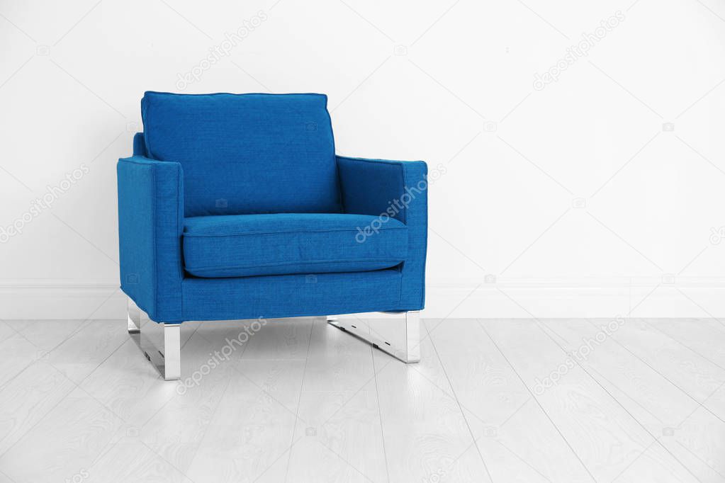 Comfortable blue armchair on white wall background