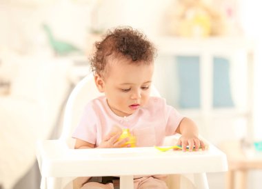 Oturma odasında kaşık ile şirin bebek