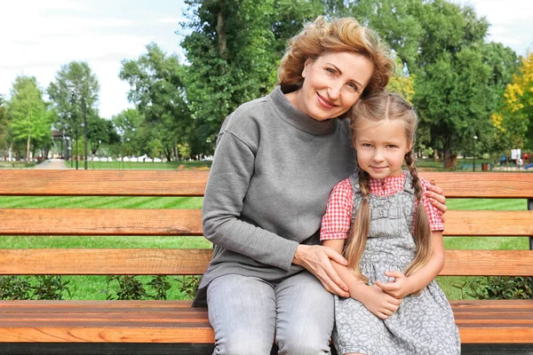 Roztomilá dívka s babičkou na lavičce v parku — Stock fotografie