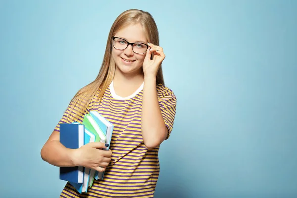 Милая девочка-подросток с книгами на цветном фоне — стоковое фото