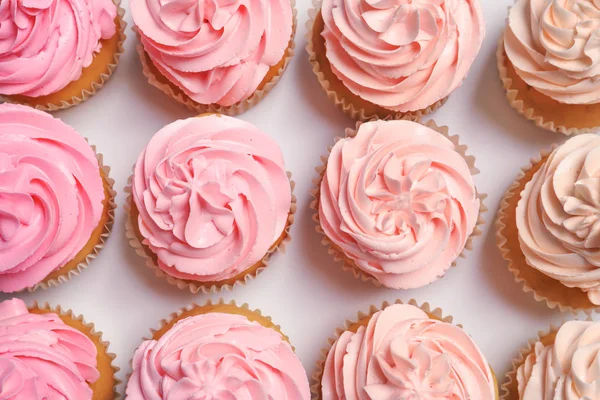 Många smaskiga cupcakes på vit bakgrund — Stockfoto