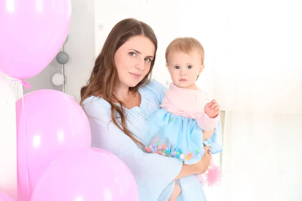 Jovem mãe segurando bebê bonito na festa de aniversário em casa — Fotografia de Stock