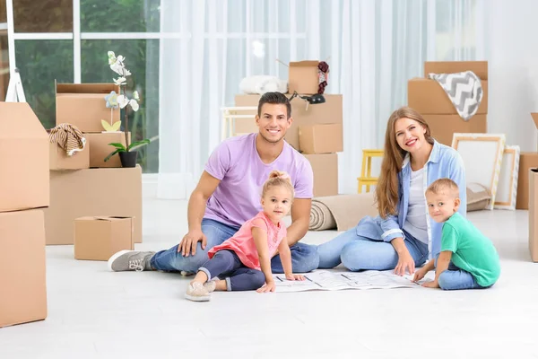 Familie studeren plan van hun nieuwe huis zittend op de vloer — Stockfoto